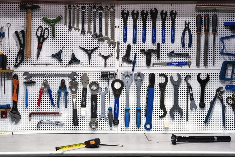 Wrenches, pliers and hand tools hung on a white pegboard above a workbench.